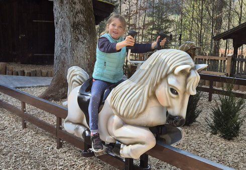 Ein Kind auf der Pferdereitbahn im Freizeitpark Ruhpolding