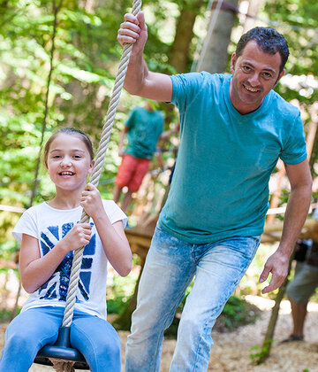Erwachsener schubst an im Waldseilgarten