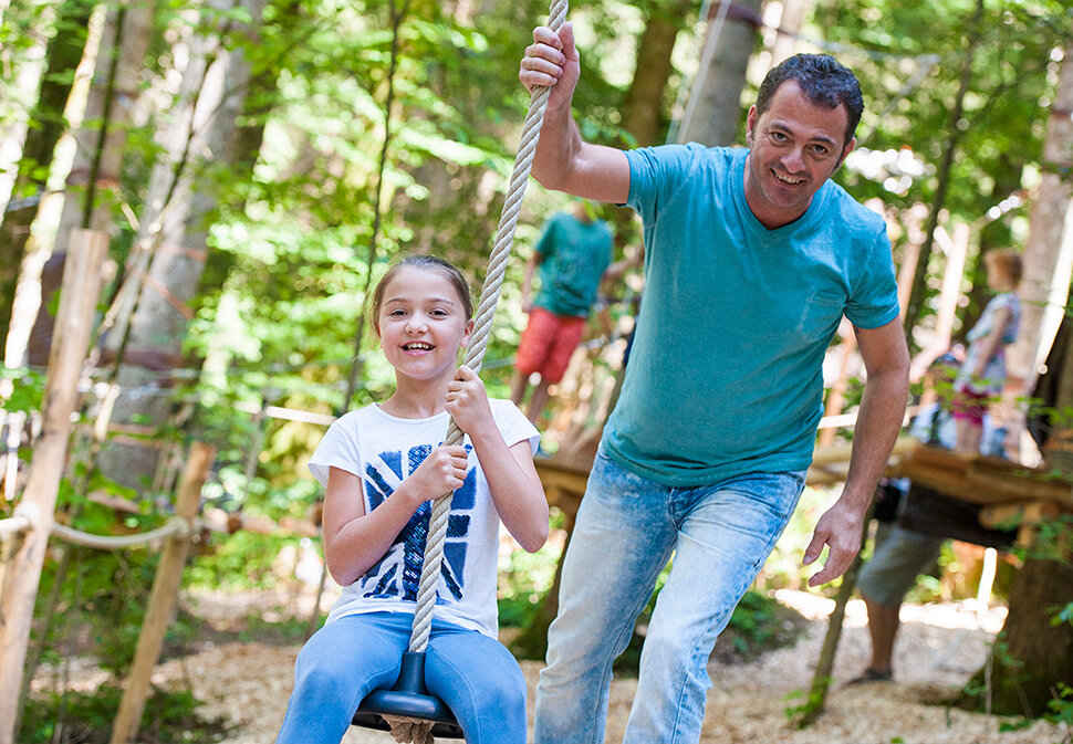Erwachsener schubst an im Waldseilgarten