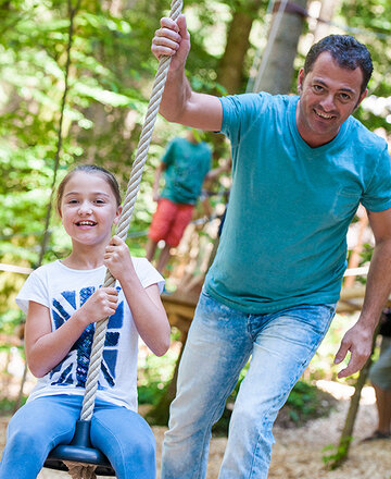 Erwachsener schubst an im Waldseilgarten